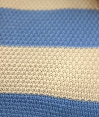 Close-up of a knitted fabric with horizontal stripes in medium blue and warm beige.