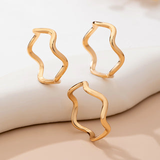Gold wavy rings on a beige surface
