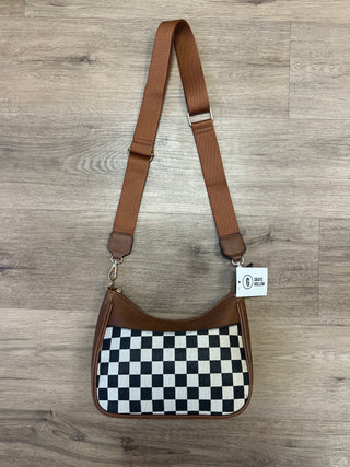 Checkered bag with brown strap on a wooden floor