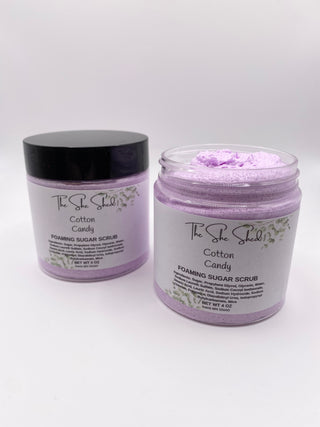 Two jars of The She Shell Cotton Candy Foaming Sugar Scrub on a white background, one closed with a black lid and one open showing the light purple scrub inside.