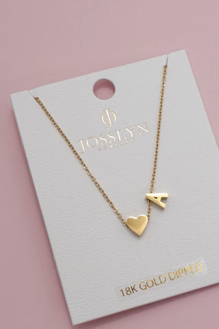 Gold necklace with heart and 'A' pendant on a Josslyn card with pink background
