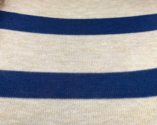 Close-up of a knit fabric with horizontal stripes, featuring a warm cream base and dark navy blue stripes.