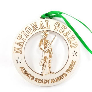 A round wooden National Guard ornament with a green ribbon hanging from the top. The ornament is light-colored wood with laser-engraved text reading 'NATIONAL GUARD' and 'ALWAYS READY ALWAYS THERE' around a central figure holding a rifle.