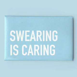 A rectangular light blue sign or magnet with bold white text reading 'SWEARING IS CARING' on a matching light blue background.