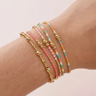 Multicolored beaded bracelets on a wrist against a light background