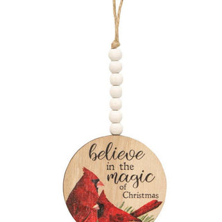 Wooden ornament with cardinal design and 'believe in the magic of Christmas' text on a white background.