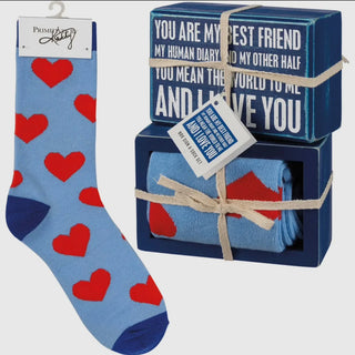 Blue socks with red hearts and a blue box with text and socks inside on a white background