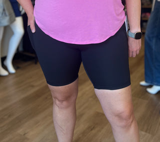 Person wearing black shorts and a pink top on a wooden floor.