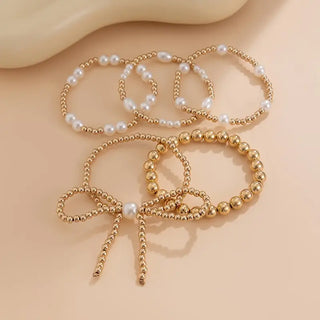 Gold beaded bracelet with pearl accents on a beige background