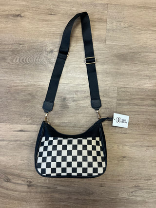 Black and white checkered handbag with a strap on a wooden surface