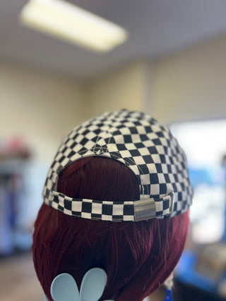 Checkered cap on a wig with a blurred indoor background
