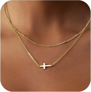 Gold necklace with a cross pendant on a mannequin.
