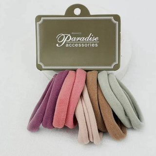 A set of six soft fabric hair ties in assorted pastel and neutral colors, attached to a brown cardboard hanger card labeled 'Paradise accessories' against a plain white background.