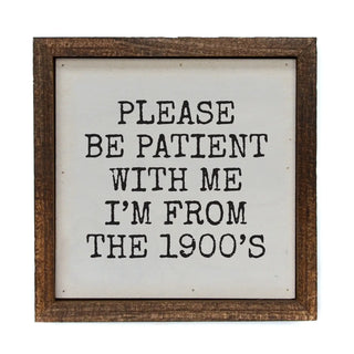A square rustic wooden sign with a distressed brown frame and a white face, featuring the text 'PLEASE BE PATIENT WITH ME I'M FROM THE 1900's' in a black typewriter-style font.