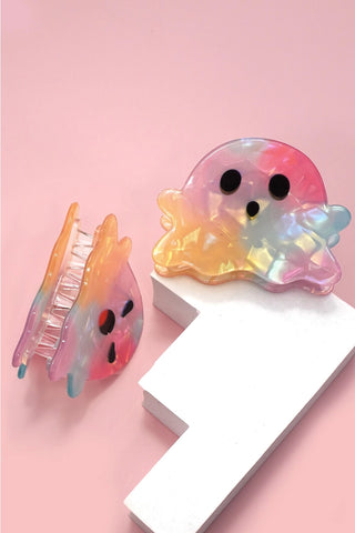 Two translucent jellyfish-shaped hair claw clips with black eyes, displayed on a pink background with one clip attached to a white display block.