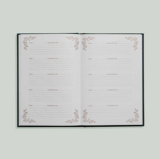 An open planner or journal with white pages, featuring delicate rose gold floral corner illustrations and multiple lined writing sections across the spread, set against a solid light gray background.