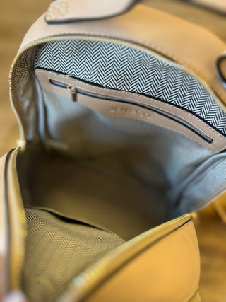 Close-up of the interior of a beige leather bag, showing a zippered pocket with a blue and white herringbone patterned lining and a faint embossed logo.