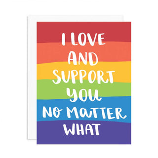 A greeting card with a rainbow striped background and white text that reads, 'I LOVE AND SUPPORT YOU NO MATTER WHAT,' shown with a white envelope behind it on a light gray background.
