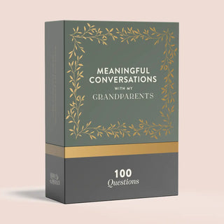 A boxed card deck titled "Meaningful Conversations with My Grandparents" shown on a plain light blush background. The box is dark green on the upper portion with a gold leafy border and white text, and dark gray on the lower portion with a gold horizontal band and white text reading "100 Questions.