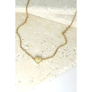 Gold heart-shaped pendant necklace on a textured stone surface