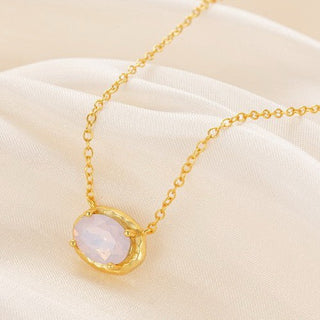 Gold necklace with a pink pendant on a beige fabric background