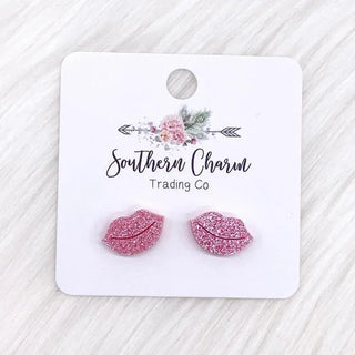 Pink glittery lip-shaped earrings on a 'Southern Charm Trading Co' card.