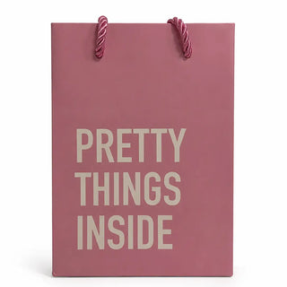 A dusty rose pink gift bag with twisted rope handles and the text 'PRETTY THINGS INSIDE' printed in a light beige serif font, set against a plain white background.