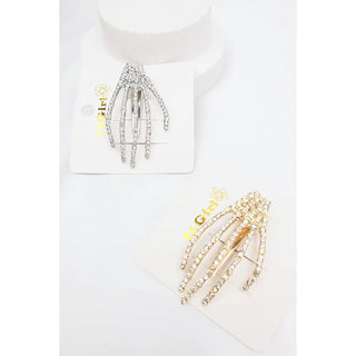 Two claw-style skeleton hand clips displayed on white cards, one silver-toned and one gold-toned, both adorned with clear rhinestones. The cards feature the 'Hi Girl' brand logo.