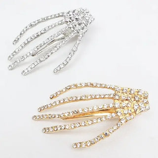 Two skeleton hand hair clips on a white background, one in silver and one in gold, both embellished with clear rhinestones.