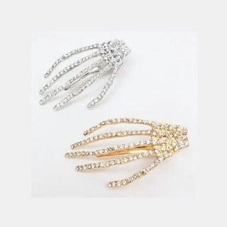Two skeleton hand-shaped hair claw clips, one in silver and one in gold, both embellished with clear rhinestones, shown on a plain white background.