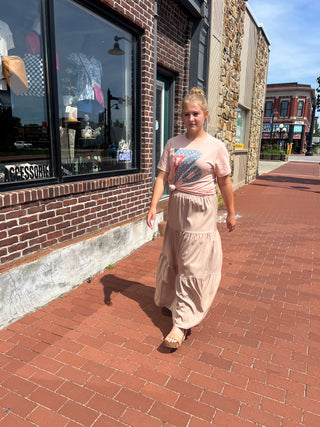 Woman walking on a brick sidewalk in front of a store with large windows.