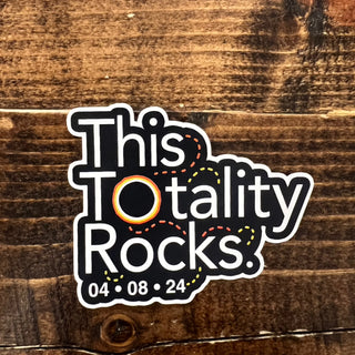 Sticker with 'This Totality Rocks' text on a wooden background