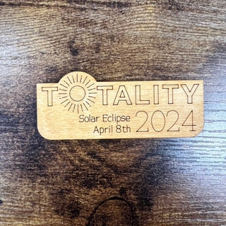 Wooden plaque with 'Totality Solar Eclipse April 8th 2024' engraved on a wooden surface