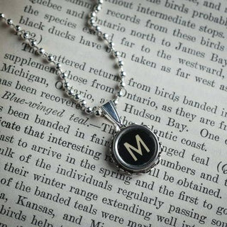 Necklace featuring a letter 'M' on an open book